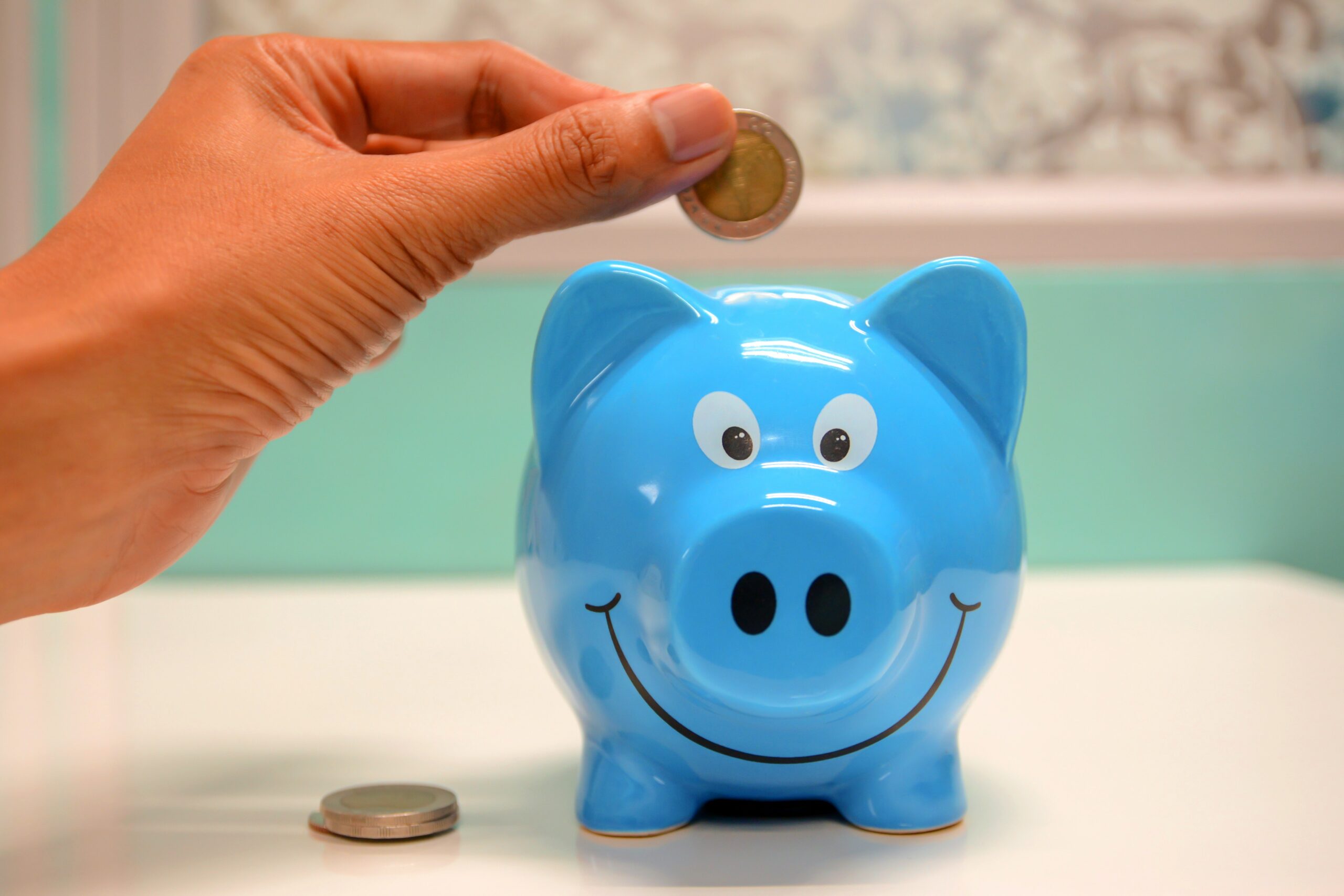 Blue Piggy money box smiling with hand and coin